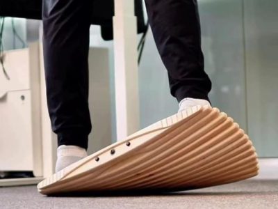 Person standing on a curved wooden standing desk balance board