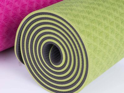 Large Salute The Sun yoga mat, 183 x 80cm, partly rolled to show its pink and green layers